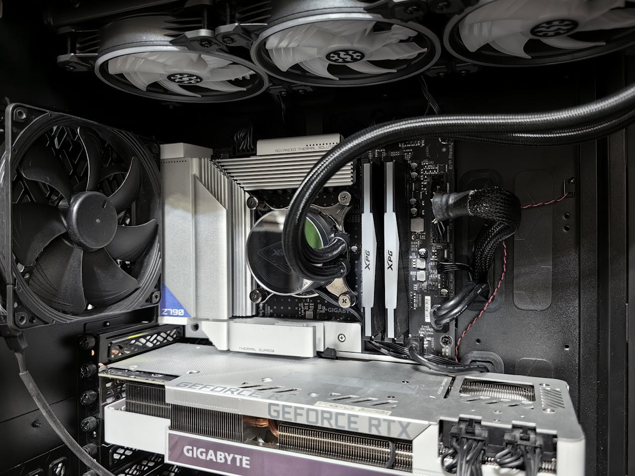 Close-up of a high-performance gaming PC build featuring a Geforce RTX graphics card and complex cooling system.